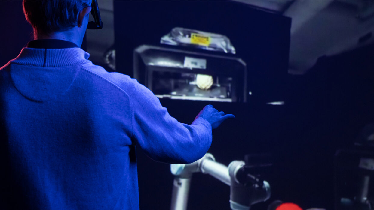 Researcher using AR headset to direct a robotic arm.