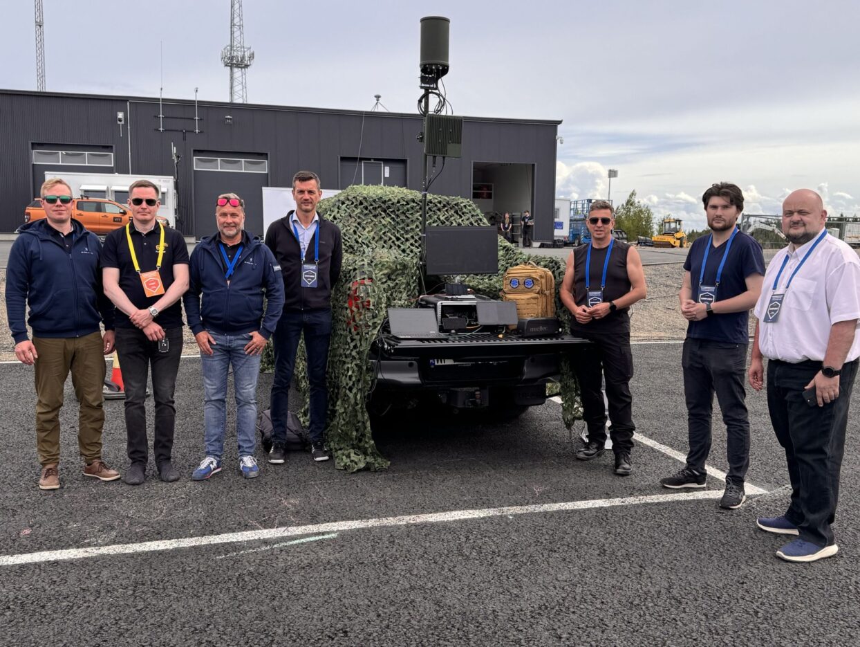 IS-Wireless and 6G Test Centre representatives beside a vehicle-mounted communications system at OuluZone during LCI-X Crucible 2-26